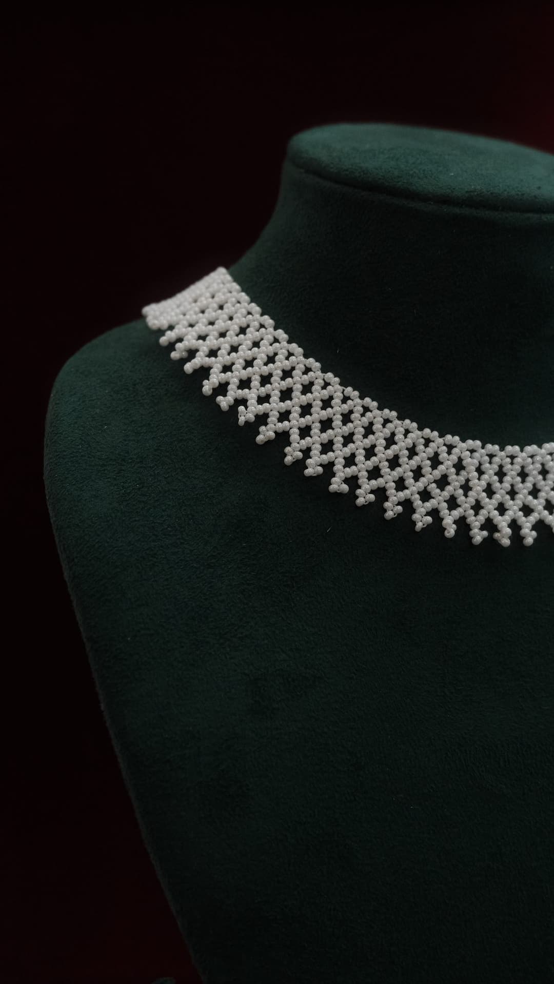 The Lace Choker in pearl on a green velvet bust